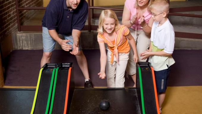 Щастливо семейство, което прекарва време заедно и играе игри в аркада, благодарение на положителното родителство